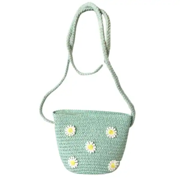 Mintgrön virkad barnväska med vita kamomillblommor och löst hängande axelrem.