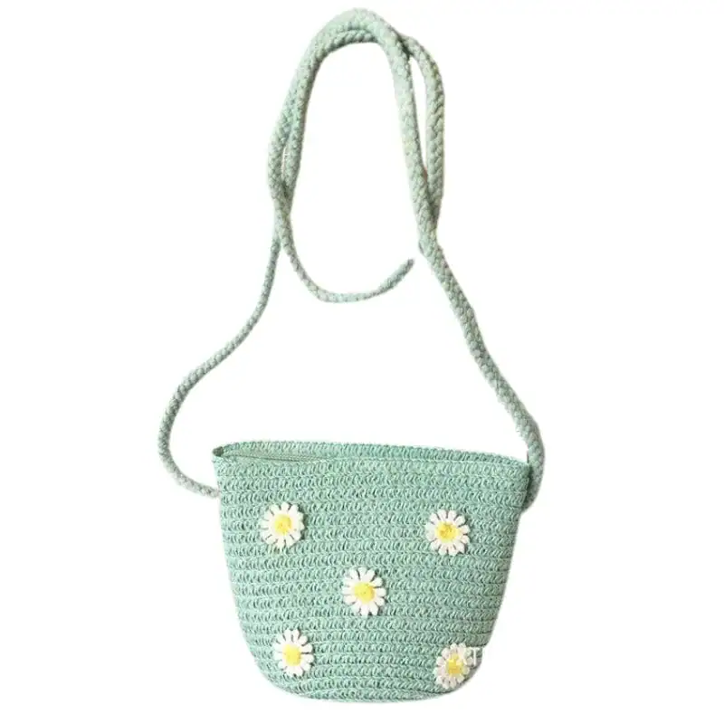 Mintgrön virkad barnväska med vita kamomillblommor och löst hängande axelrem.