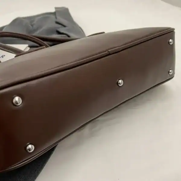 Mörkbrun bowlingväska med silverfärgade snäckor och elegant design.