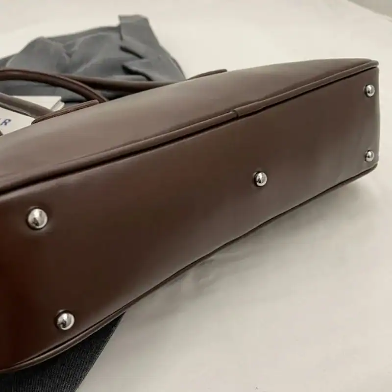 Mörkbrun bowlingväska med silverfärgade snäckor och elegant design.