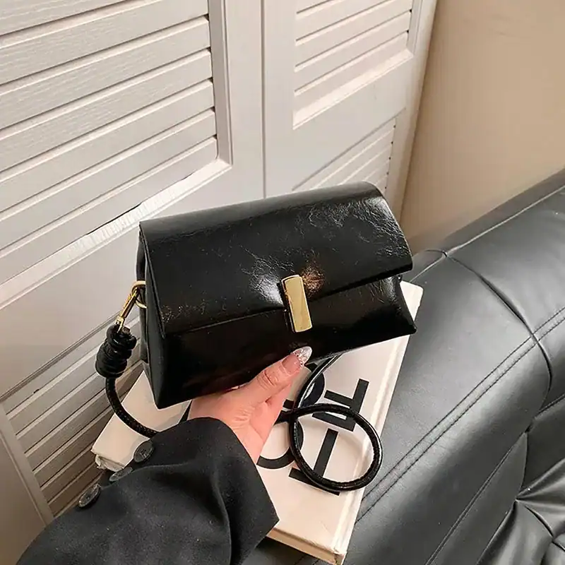 Mörkbrun handväska med guldaccent, hållbart läderdesign och axelrem.