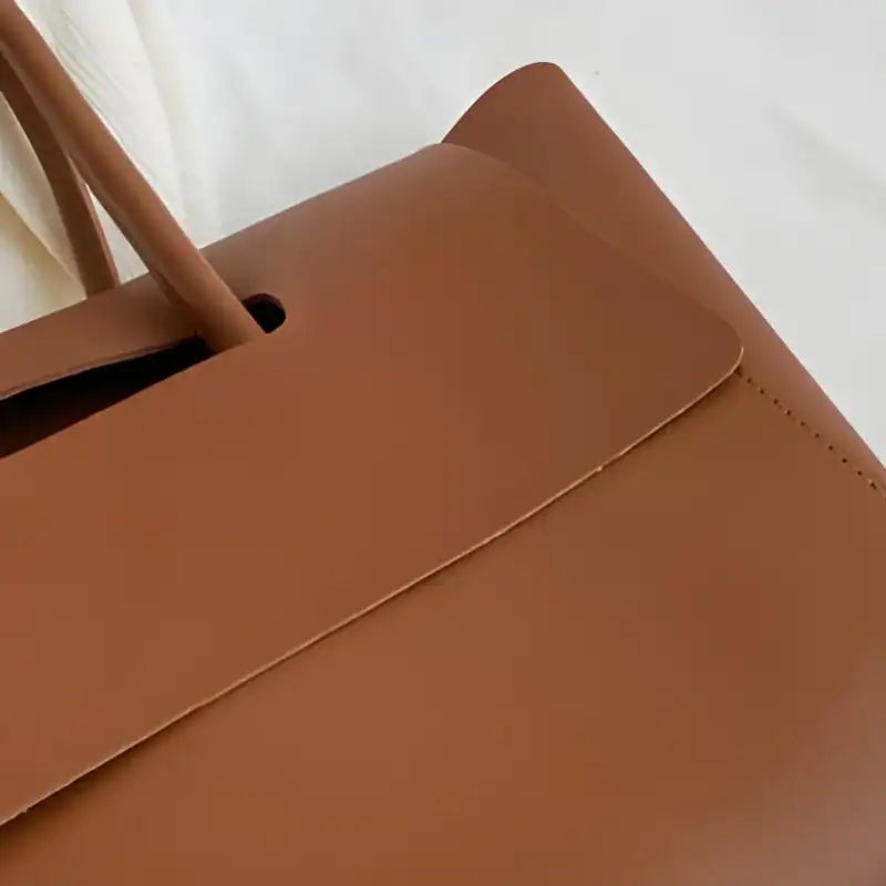 Mörkbrun shopper axelväska med läderhandtag och exakt sömnad.