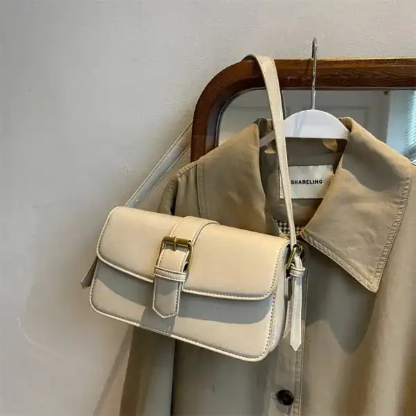 Mörkgrön liten axelremsväska med guldtonad snäcka och elegant design.