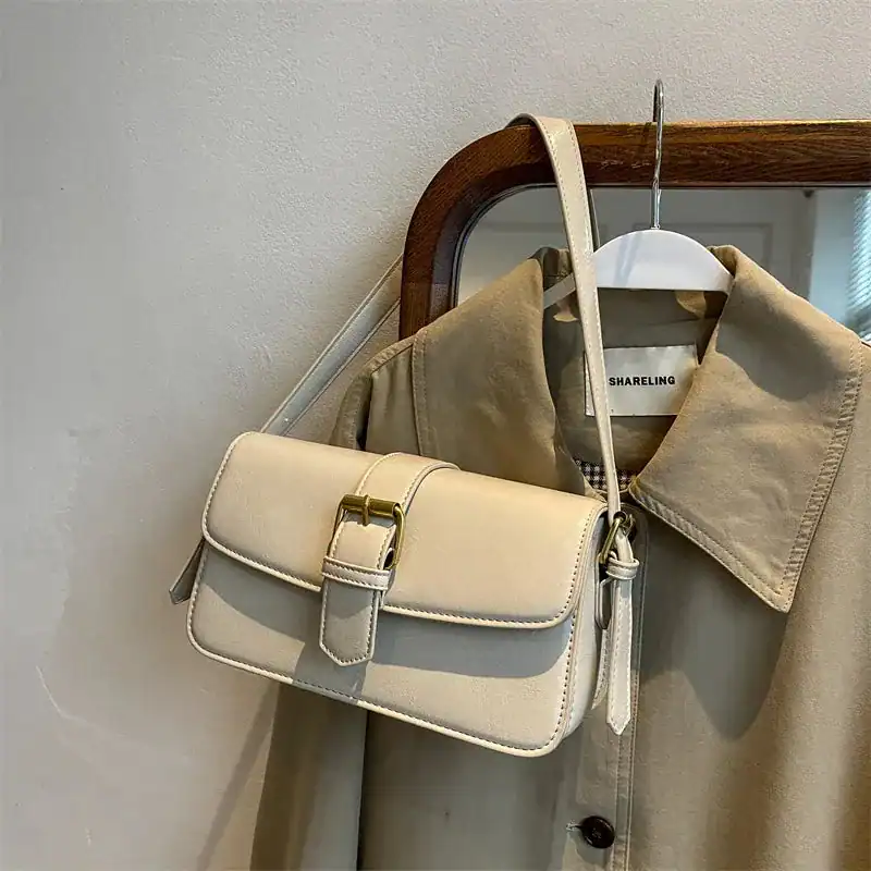 Mörkgrön liten axelremsväska med guldtonad snäcka och elegant design.