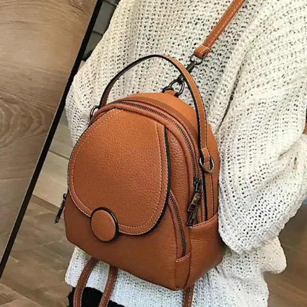 Orange liten ryggsäck i läder med handtag och axelrem, passar perfekt för daglig användning.