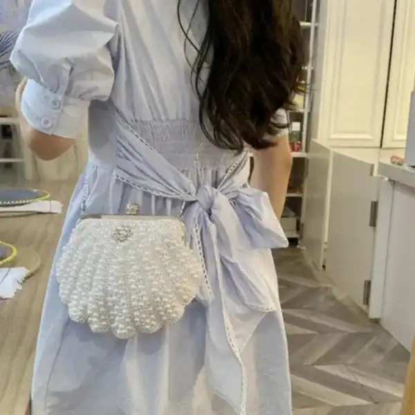 Pärlclutch snäckform i vit, eleganta axelväska med pärlor och smycken.