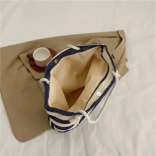 Randig strandväska med blå-vit randigt mönster och trådhandtag.