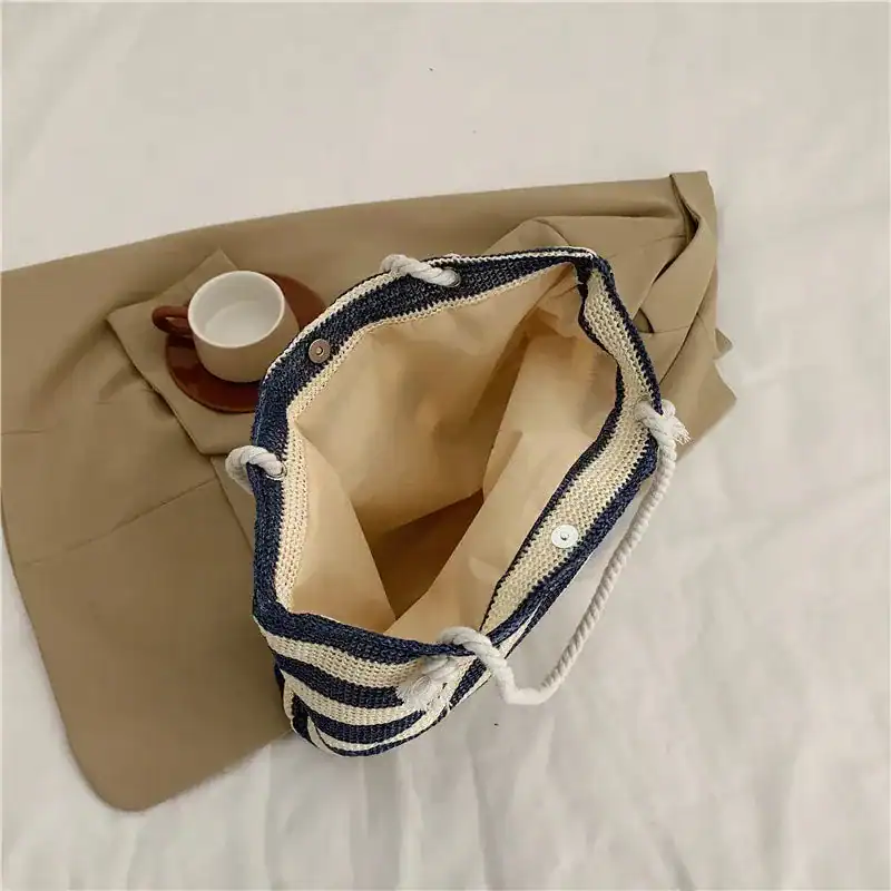 Randig strandväska med blå-vit randigt mönster och trådhandtag.