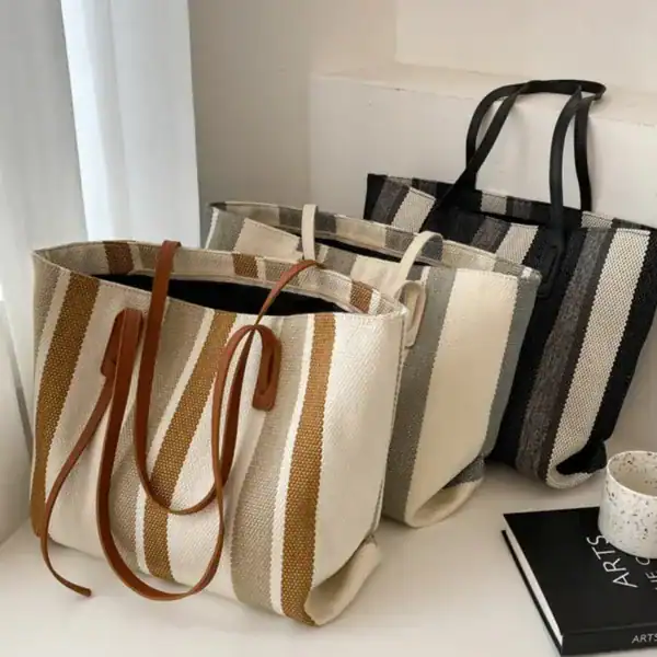 Randig svartvit shoppingväska med läderhandtag, trendig och praktisk för daglig användning.