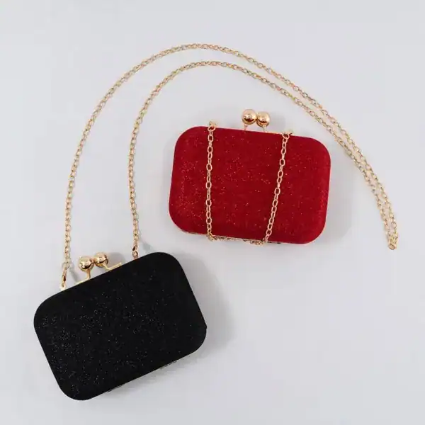Röd och svart glitterclutch med gyllene kedja och knappmekanism.