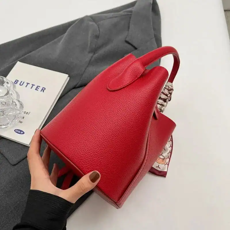 Röd hinkväska i läder med handtag, modeaccessoarer för kvinnor.