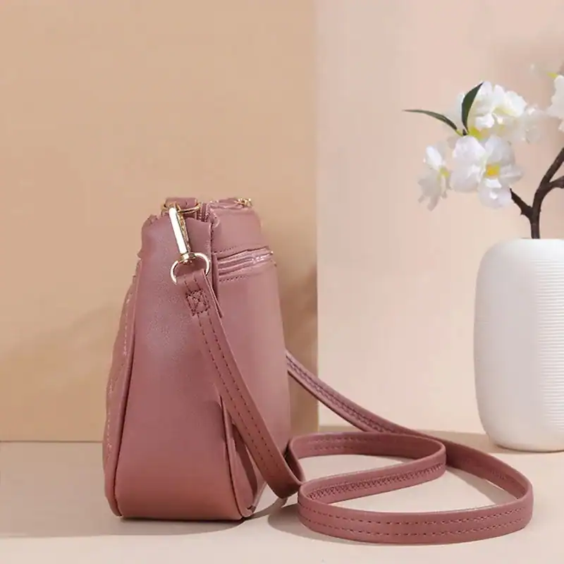 Rosa axelväska med axelrem, läderliknande material och guldaktiga detaljer.