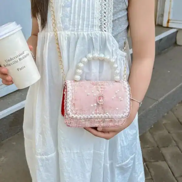 Rosa barnväska med pärlor och gyllene kedja, perfekt för flickor.