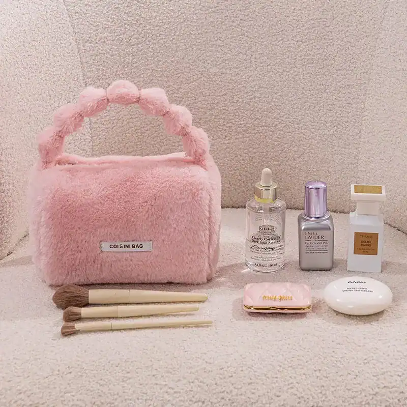 Rosa fluffig väska med pärlformad handtag och kosmetikprodukter.