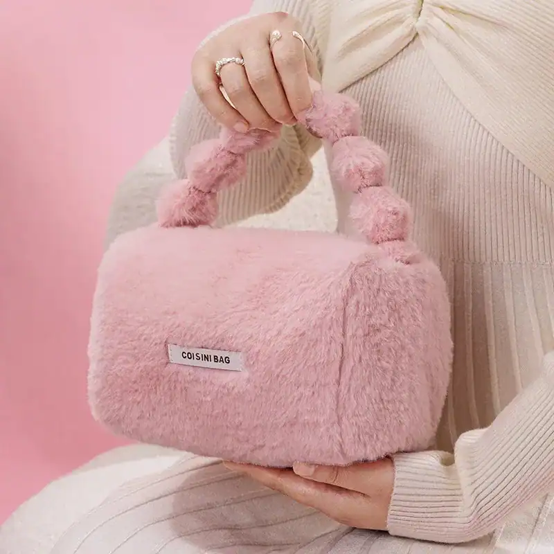 Rosa fluffig väska med pärlformade handtag och etikett.