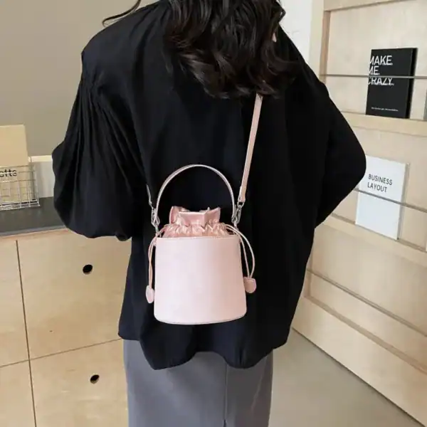 Rosa hinkväska med dragkedja, bärt som axelväska på modell.