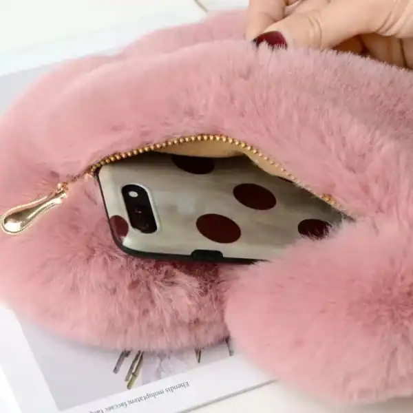 Rosa hjärtväska i päls med mobil i fickan.