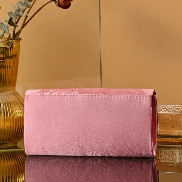 Rosa kuvertväska i sammet med strukturerad design och elegant finish.
