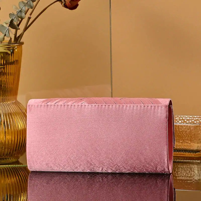 Rosa kuvertväska i sammet med strukturerad design och elegant finish.