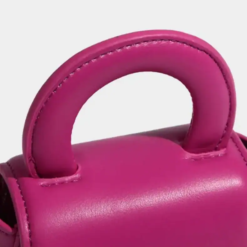 Rosa minihjärtväska med kedja, närbild på handtaget och läderdetaljer.