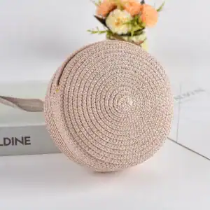 Rosa rund stråväska med spiral mönster och läderrem.