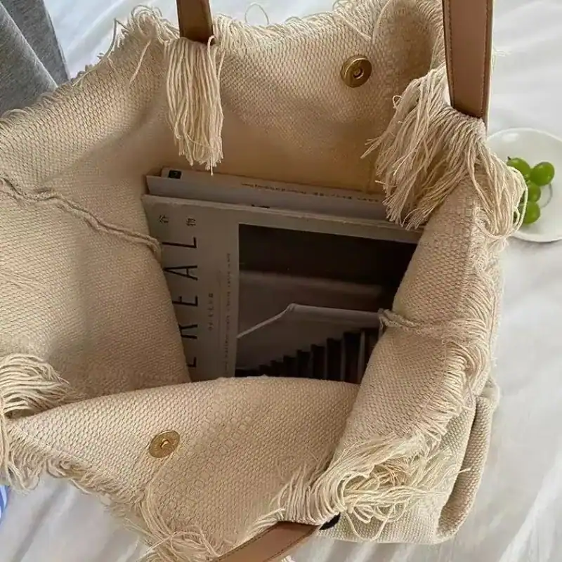 Strandväska i beige med fransar och text, perfekt för sommar och strand.