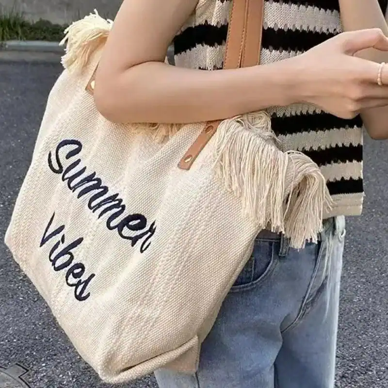 Rosa strandväska med text 'Summer Vibes', fransad axelväska för sommar.