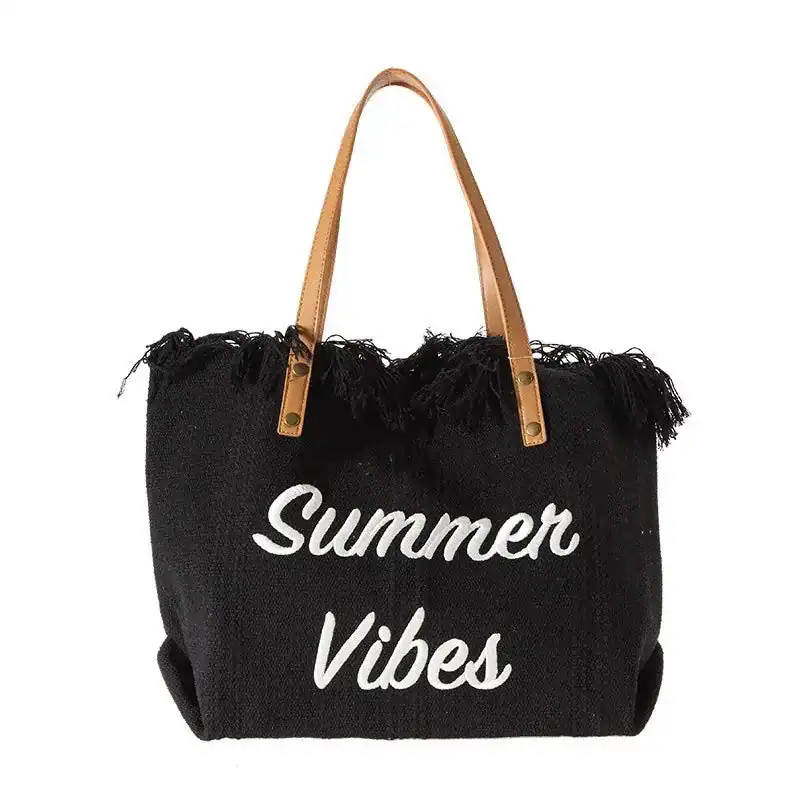 Svart strandväska med text Summer Vibes och fransar, lämplig för sommar och strand.