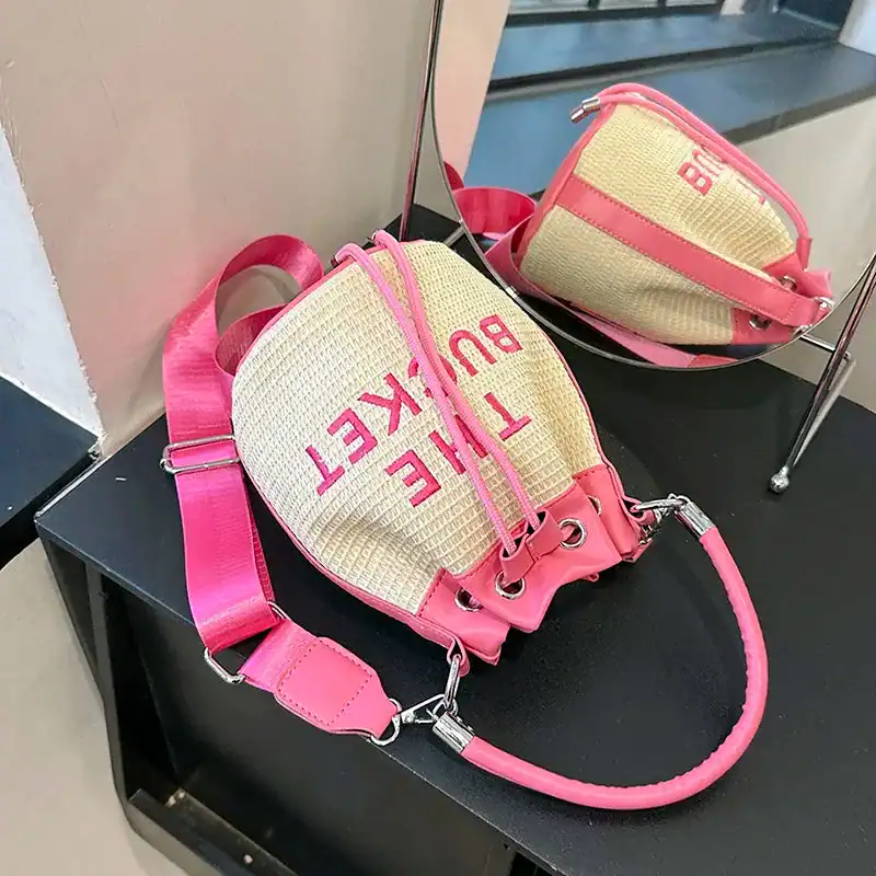 Rosa stråväska med text 'THE BUCKET' och axelrem, sommarväska för kvinnor.
