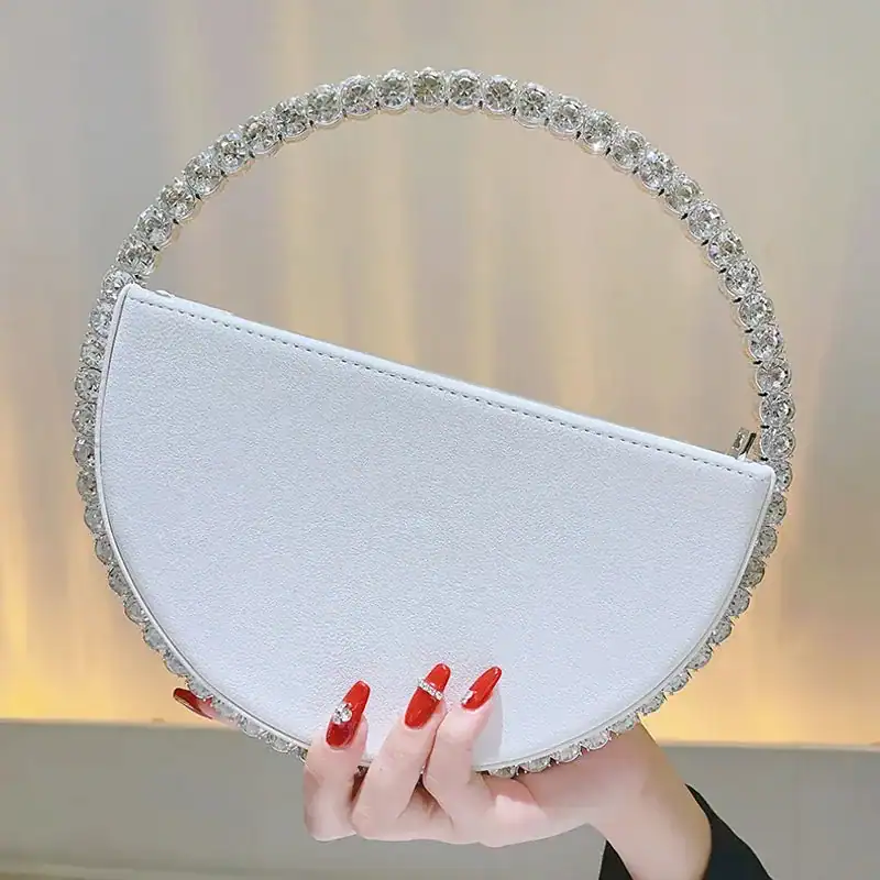 Vit rund clutch med strass och silverfärgad handtag, perfekt för festlig tillfälle.