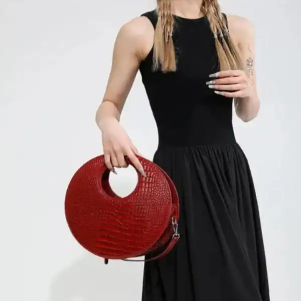 Röd rund väska med hål, modeaccessoarer, handväska, axelväska, läder, krokodilsmönster.
