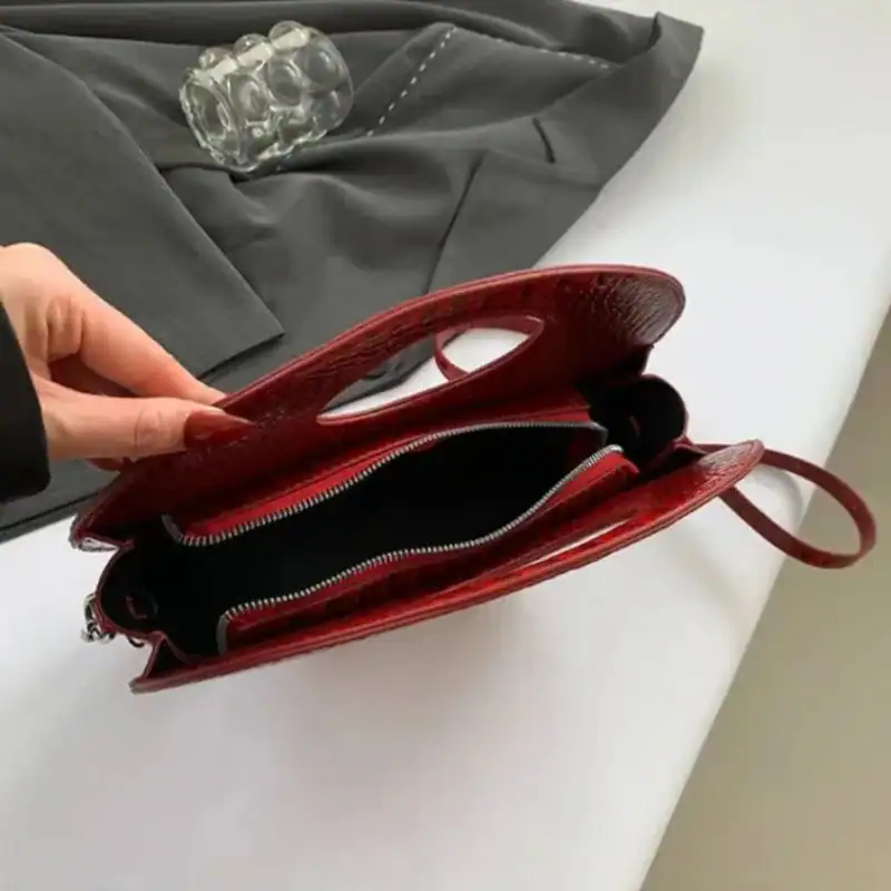 Röd rund väska med hål, öppen vy, läderliknande textur.
