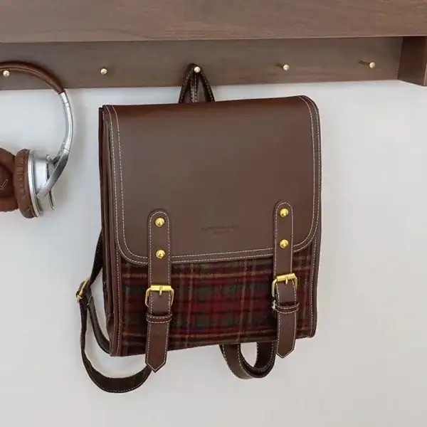 Rutig ryggsäck i brunt läder med rutig textil och guldtonade snöringar.