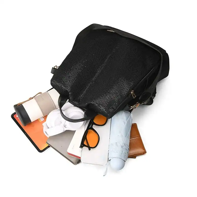 Svart ryggsäck canvas med öppen topp och innehåll som mobil, glasögon och paraply.