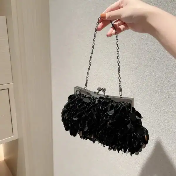 Svart metallisk klädselplåt clutch med kedjehantering och plåtdekor.