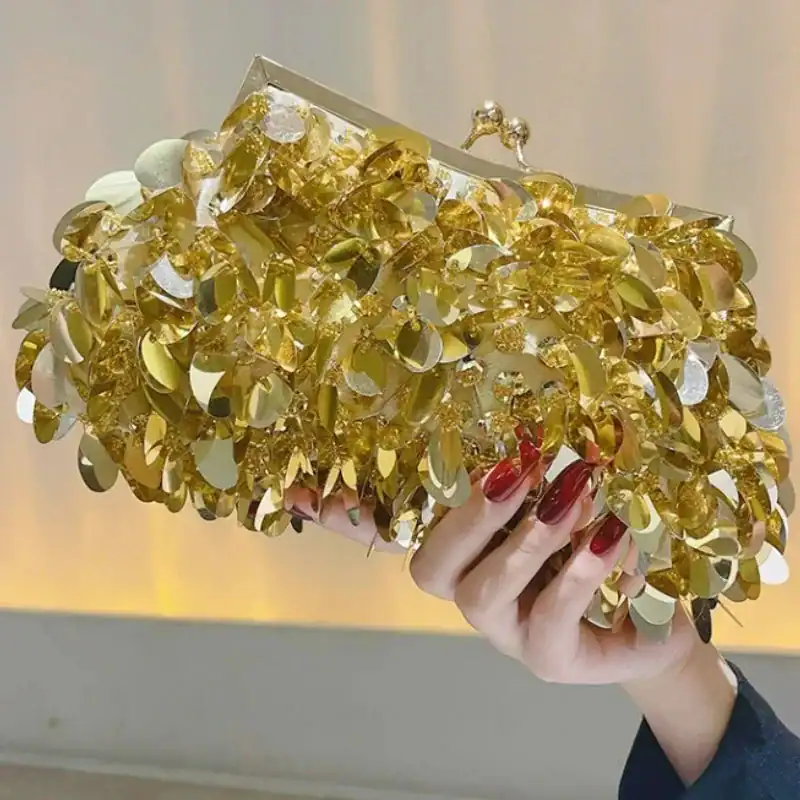 Guldpläterad clutch med bladmotiv och knapplås, elegant för fest och kväll.