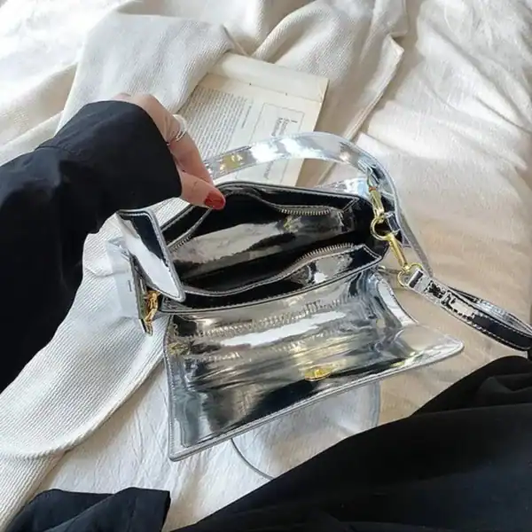 Silverfärgad Axelväska med genomskinlig design och guldaktiga dragkedjor.