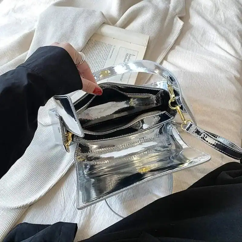 Silverfärgad Axelväska med genomskinlig design och guldaktiga dragkedjor.