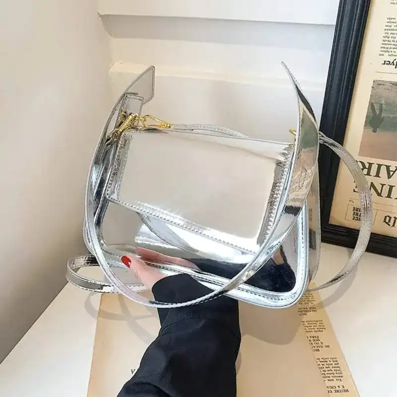 Silverfärgad Axelväska med genomskinlig design och gyllene snäckor.