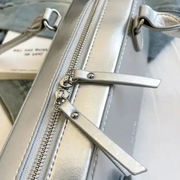 Silvrig axelremsväska med metallisk dragkedja och eleganta detaljer.