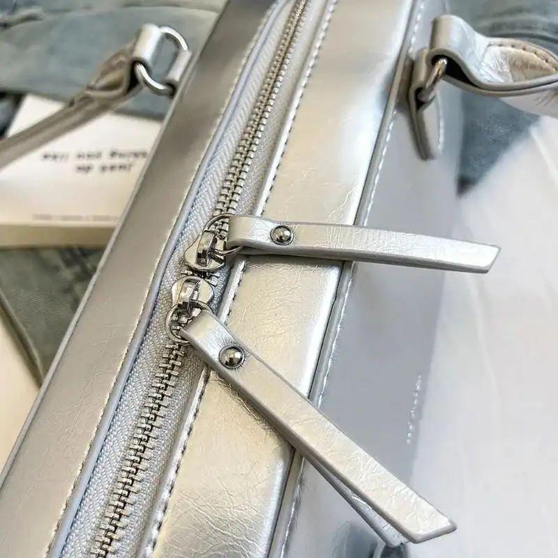 Silvrig axelremsväska med metallisk dragkedja och eleganta detaljer.