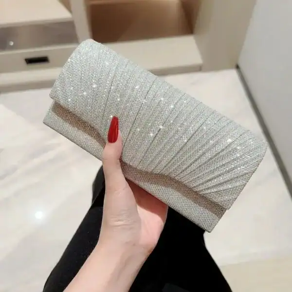 Silvrig glitterclutch med plockad design och röd nagellack.