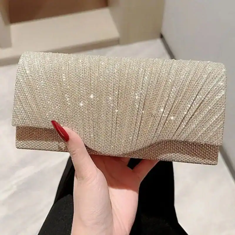 Silvrig glitterclutch med strukturerad yta och röd nagellack.