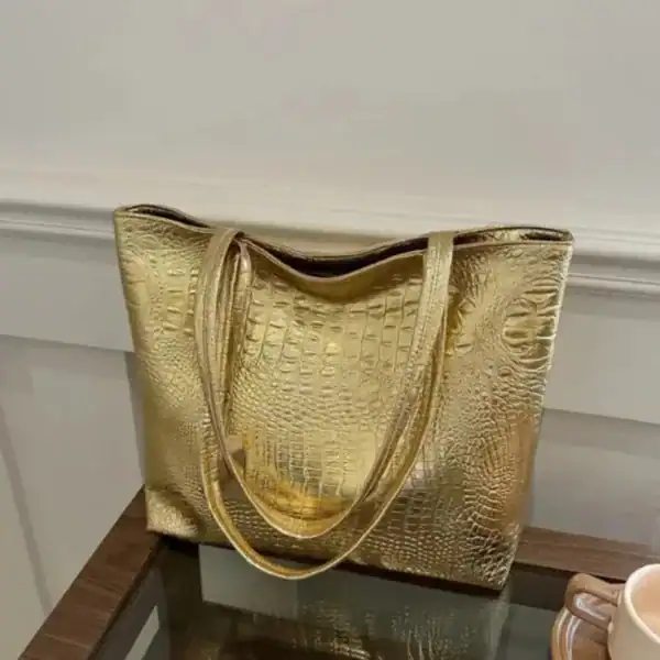 Silvrig väska med krokodilsmönster, elegant axelväska i guldtoner.