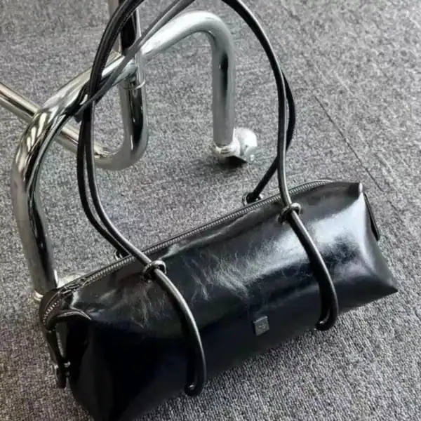 Svart avlång väska med glansigt läder och svarta handtag.
