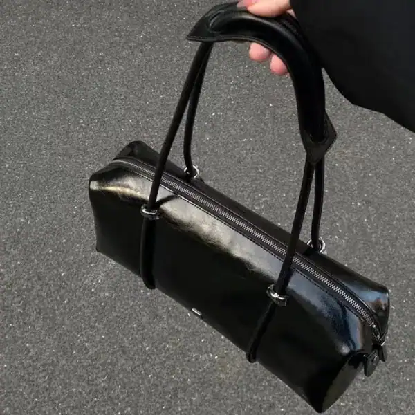 Svart avlång väska med glansig yta och handtag, perfekt för vardag och mode.
