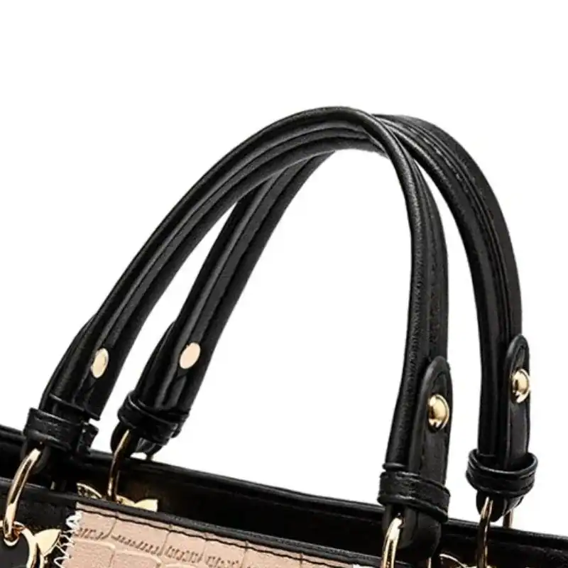 Svart beige vit handväska med svarta handtag och guldtonade detaljer.