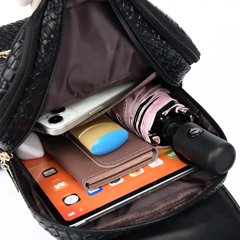 Svart flätad ryggsäck med innehåll, mobil, paraply och tablet.