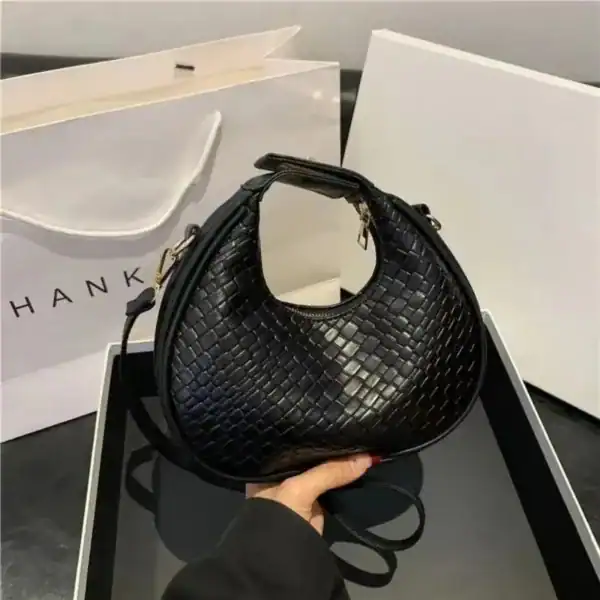 Svart flätad väska med handtag och axelrem, elegant och trendig.