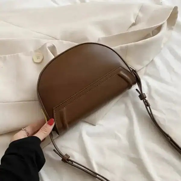 Svart halvmåneväska med lock, elegant axelväska i läder för vardag och mode.